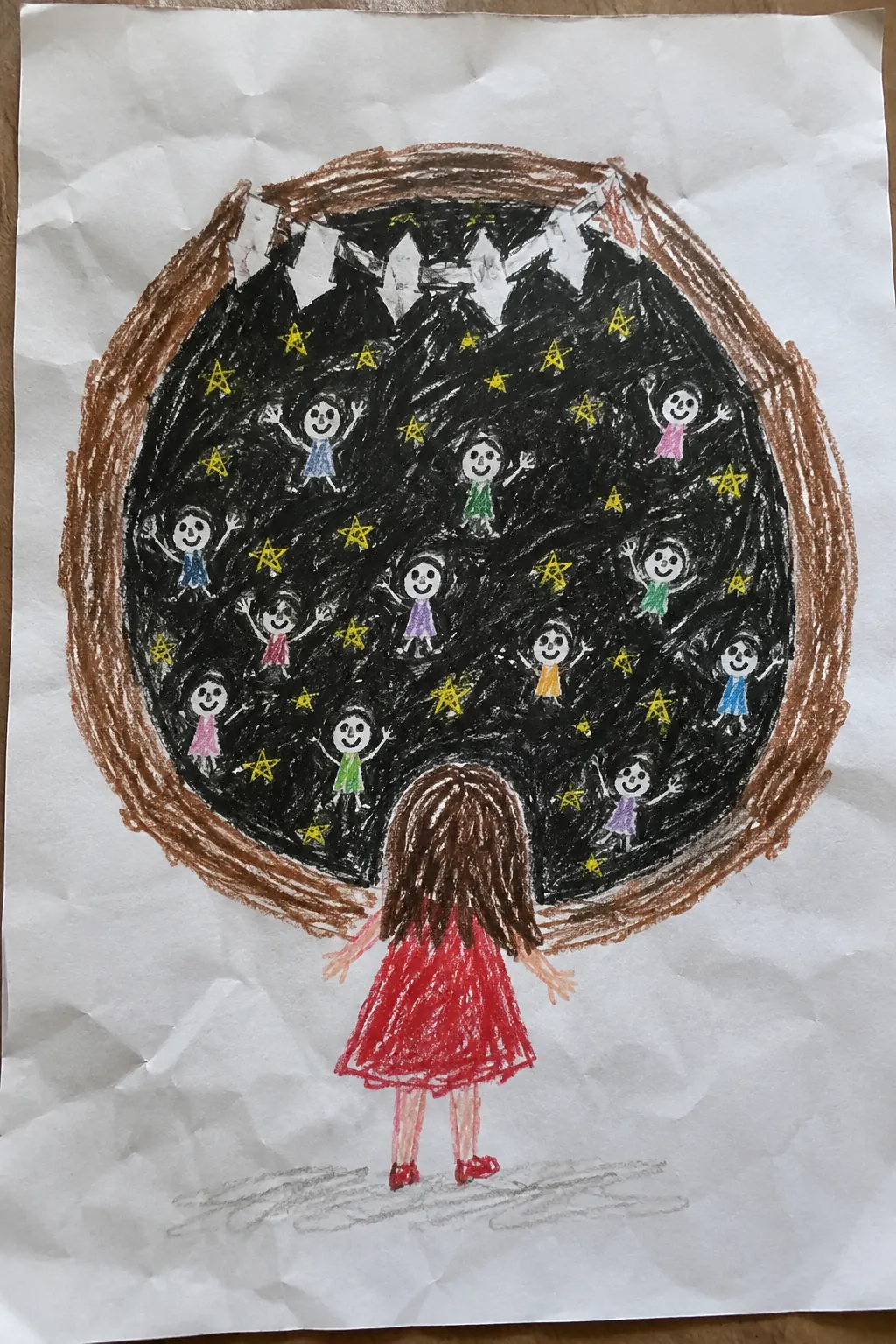 子どものクレヨン画。黒くて丸いものの中に、小さな人がたくさんいて、その前に赤い服の女の子が立っている。